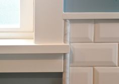 the corner of a kitchen counter with white tile on it and a window in the background