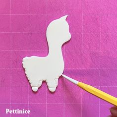 someone is cutting out the shape of a llama with a yellow handled toothbrush