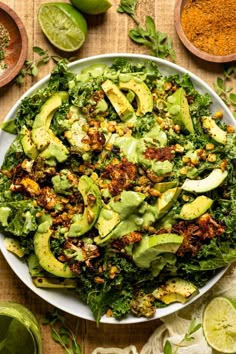 a white bowl filled with green vegetables and avocado on top of a wooden table