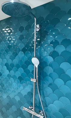 a shower head with blue tiles in the background