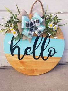 a wooden sign with the word hello painted on it and flowers in front of it