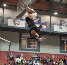 a woman in black shirt and shorts doing a handstand on a gymnastics court