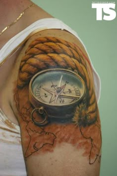 a man with tattoos on his arm holding a compass