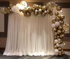 the balloon arch is decorated with gold and white balloons