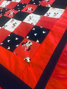 a red and black quilt with mickey mouses on it