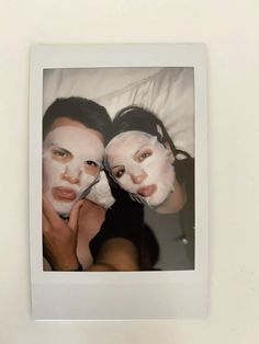 two women with facial masks on their faces are posing for a photo in front of a white wall