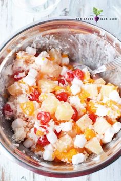 a glass bowl filled with fruit salad on top of a wooden table