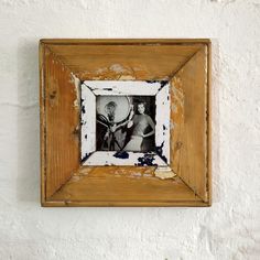 an old wooden frame with a tennis racket in it on a white brick wall