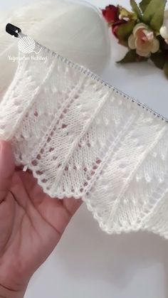 a hand holding a piece of white lace next to flowers and a pair of scissors