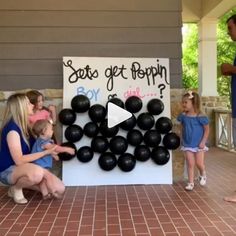 a woman kneeling down next to a sign with balloons on it and people standing around