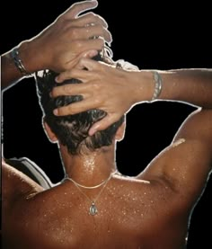 the back of a man's head with his hands on his hair and wearing bracelets