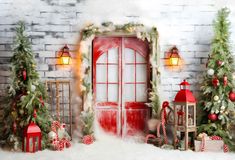 a red door surrounded by christmas trees and presents in front of a white brick wall