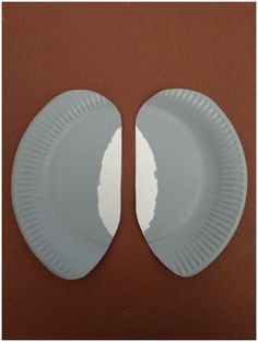 two white paper plates sitting on top of a brown table