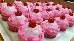 cupcakes with pink frosting and cherries on top are arranged in a row