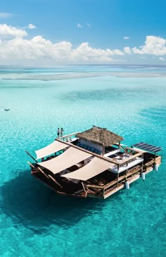 a boat floating in the middle of clear blue ocean water with people standing on it