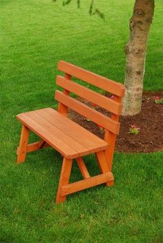 a wooden bench sitting in the grass next to a tree