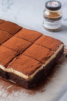 there is a chocolate cake with white frosting on the table next to a jar of peanut butter