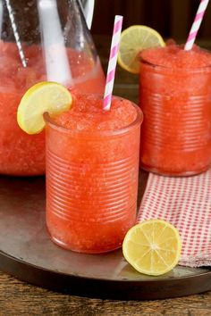 two glasses filled with watermelon and lemonade sit on a plate next to a pitcher