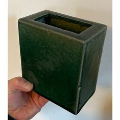 a hand is holding a green square vase