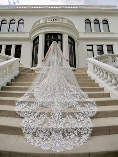 a woman in a wedding dress standing on some steps with a veil over her head