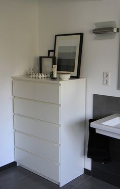 a white dresser sitting next to a bathroom sink