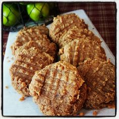 some cookies are sitting on a white plate with apples in the backgroung