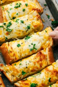 someone is holding up some cheesy bread on a baking sheet with cheese and parsley