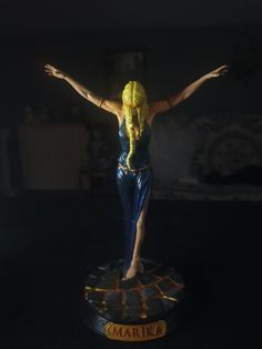 a statue of a woman with her arms outstretched in the air on top of a table