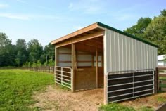 a small horse barn in the middle of a field