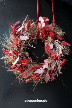 a wreath with red flowers hanging from it's side on a black background that says strassbar de