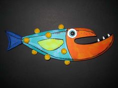 an orange and blue fish with yellow dots on it's eyes, sitting on a black surface