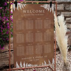 a welcome sign with flowers in the background and a planter filled with purple flowers