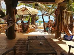 an outdoor area with hammocks, tables and chairs