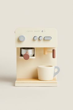 a miniature coffee maker with a cup and saucer