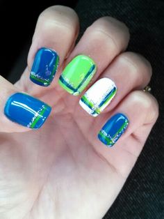 a person with blue and green nail polish on their nails