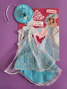 the doll is wearing a blue dress with white laces and a hat on it