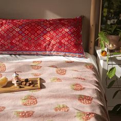 a bed topped with a pink bedspread covered in fruit