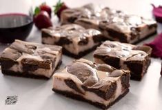 chocolate brownies with marshmallow frosting and strawberries next to them on a table