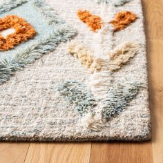 an area rug on the floor with various colors and shapes, including oranges, browns, and blue