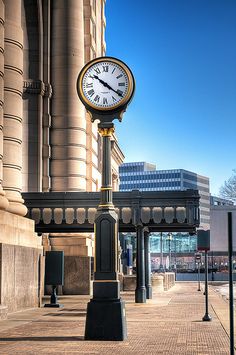 there is a clock that is on the sidewalk