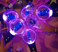 several people are sitting at a table with purple lights on their hands and one person is holding a cell phone