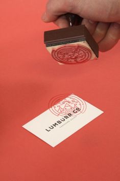 a stamper is being used to write on a piece of paper that has been placed in front of a red background