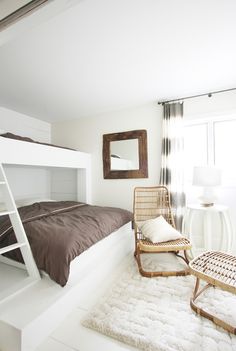 a bedroom with a bunk bed and chair next to a white rug on the floor