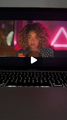 an open laptop computer sitting on top of a wooden table next to a pink neon sign