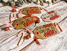 christmas tags with candy canes and snowflakes hanging from strings on wooden table