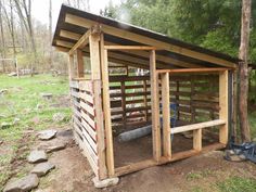 a small wooden shed in the middle of a field with rocks and trees around it