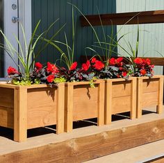 three wooden planters filled with red flowers sitting on a bench next to a building