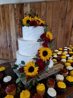 a wedding cake with sunflowers and other cupcakes