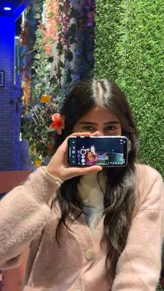 a woman taking a selfie with her cell phone in front of a green wall