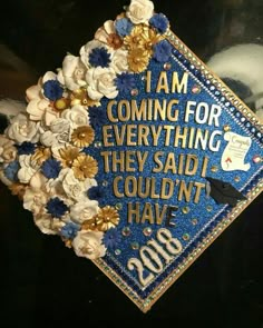 a blue graduation cap decorated with flowers and writing that says i am coming for everything they said i couldn't have